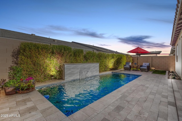 pool at dusk with a patio area and pool water feature