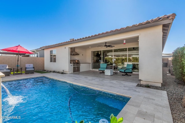 rear view of house with a fenced in pool, ceiling fan, a patio, pool water feature, and an outdoor kitchen