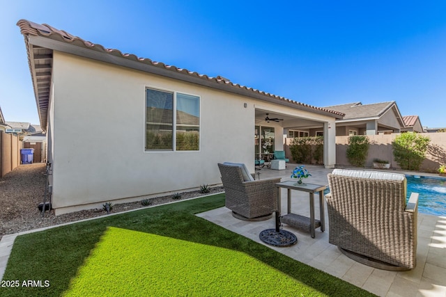 rear view of property featuring a fenced in pool, a patio, a yard, and ceiling fan