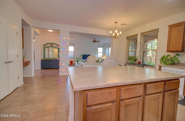 kitchen with light tile patterned floors, ceiling fan with notable chandelier, decorative light fixtures, and a kitchen island