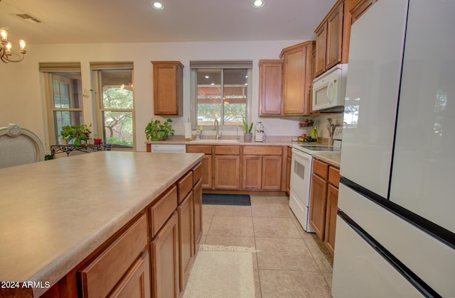 kitchen featuring sink, light tile patterned floors, white appliances, and an inviting chandelier