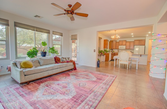 living room featuring light tile patterned floors, ceiling fan with notable chandelier, and a healthy amount of sunlight