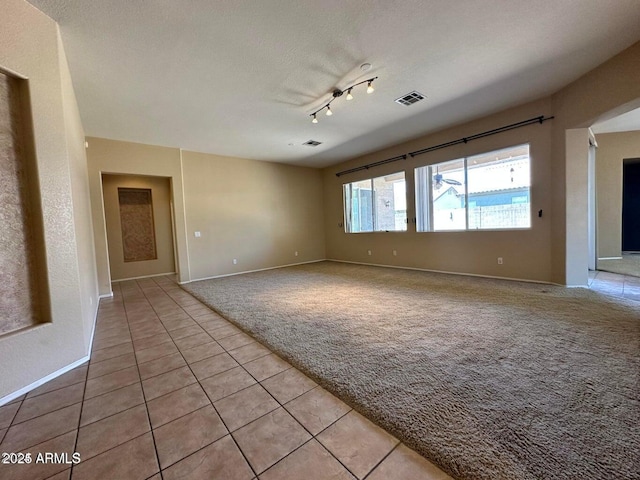 unfurnished room with light tile patterned flooring, track lighting, and a textured ceiling