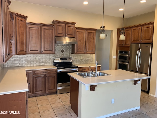 kitchen featuring stainless steel appliances, sink, a center island with sink, and a kitchen bar