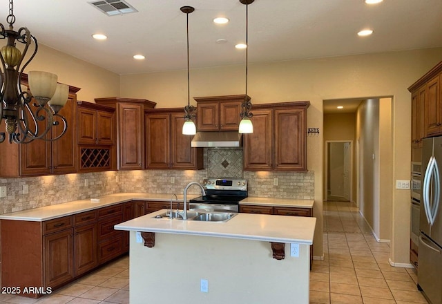 kitchen with sink, light tile patterned floors, hanging light fixtures, and a center island with sink