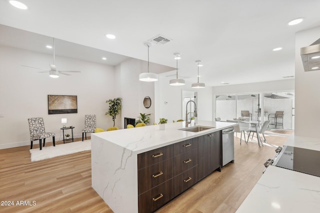 kitchen with hanging light fixtures, sink, light stone counters, and light hardwood / wood-style flooring