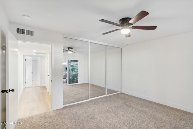 unfurnished bedroom featuring a closet, light carpet, and ceiling fan