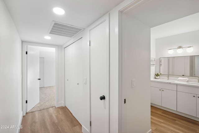 corridor featuring light wood-type flooring and sink