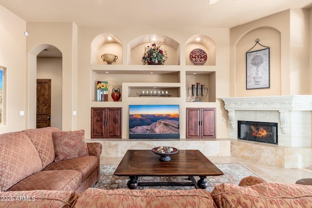 living room featuring a premium fireplace, arched walkways, and built in features