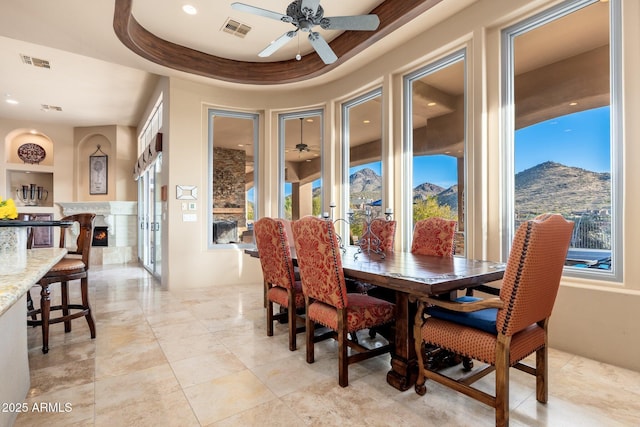 dining room with visible vents, a ceiling fan, a raised ceiling, and a fireplace