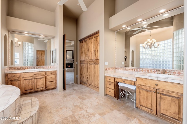 bathroom featuring two vanities, tasteful backsplash, ceiling fan with notable chandelier, and a sink