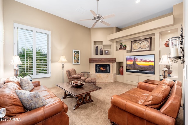 living area featuring a tile fireplace, ceiling fan, and carpet floors