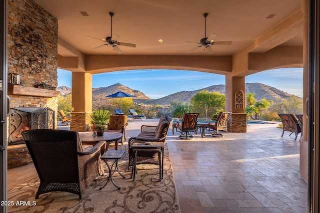 view of patio / terrace featuring ceiling fan, a mountain view, a fenced in pool, and an outdoor stone fireplace