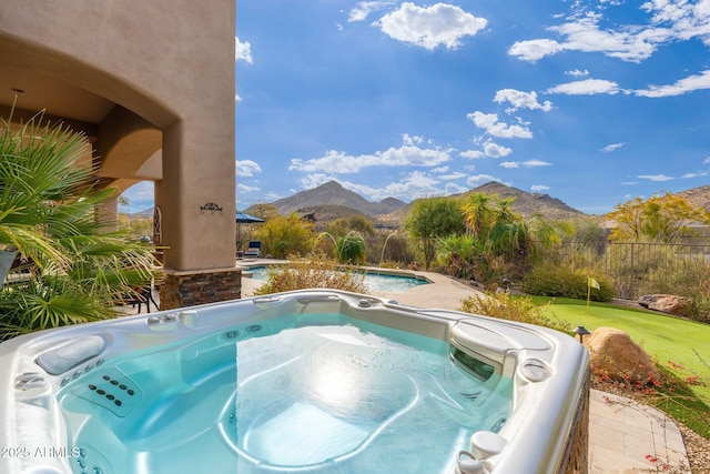 view of swimming pool featuring a mountain view, fence, and a hot tub