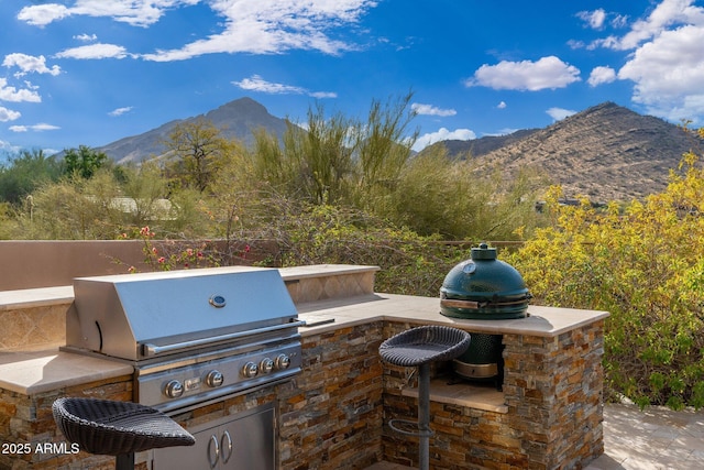 view of patio featuring grilling area, a mountain view, and exterior kitchen