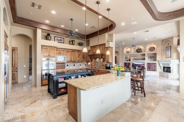kitchen with built in features, a ceiling fan, visible vents, appliances with stainless steel finishes, and arched walkways