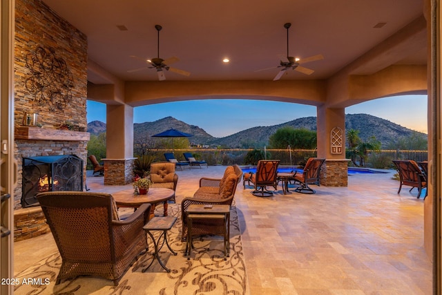 view of patio / terrace with a mountain view, fence, an outdoor stone fireplace, and a fenced in pool