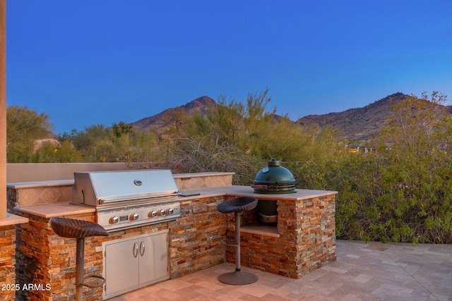 view of patio / terrace with a mountain view, area for grilling, and an outdoor kitchen