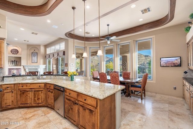 kitchen with brown cabinetry, light stone counters, a sink, and visible vents