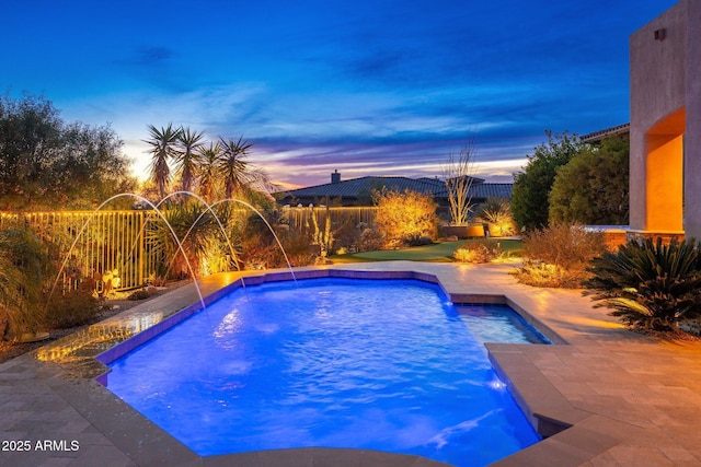 pool at dusk featuring an outdoor pool, fence, and a patio area