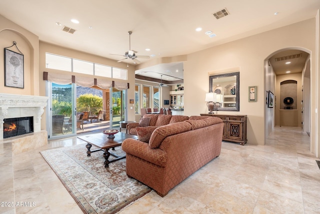 living room with a fireplace, visible vents, and ceiling fan