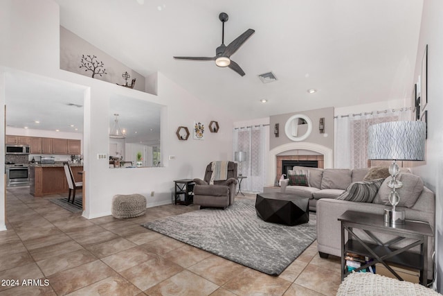 tiled living room with high vaulted ceiling, ceiling fan, and a tile fireplace