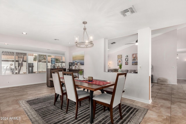 dining space with tile patterned flooring, ceiling fan with notable chandelier, and vaulted ceiling