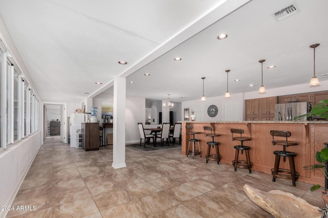 kitchen with stainless steel refrigerator, hanging light fixtures, a kitchen breakfast bar, kitchen peninsula, and a chandelier