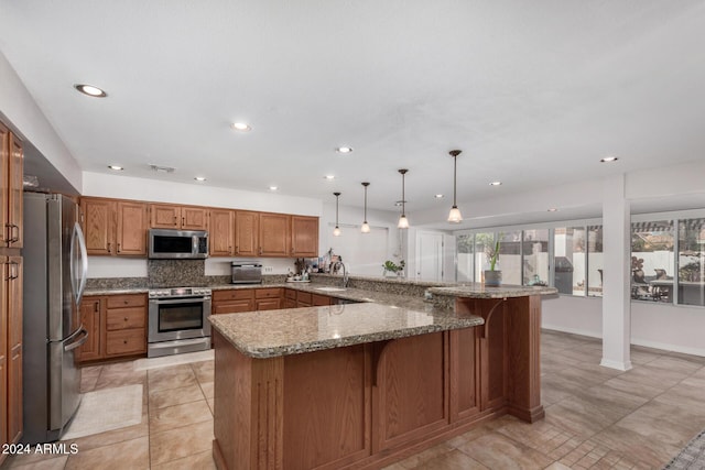 kitchen with kitchen peninsula, light stone countertops, a kitchen breakfast bar, stainless steel appliances, and pendant lighting