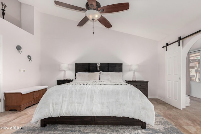 bedroom with ceiling fan, a barn door, and lofted ceiling