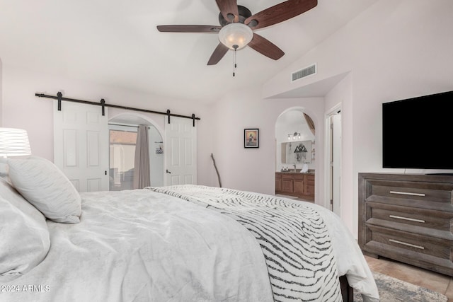 bedroom featuring a barn door, ensuite bathroom, ceiling fan, and lofted ceiling