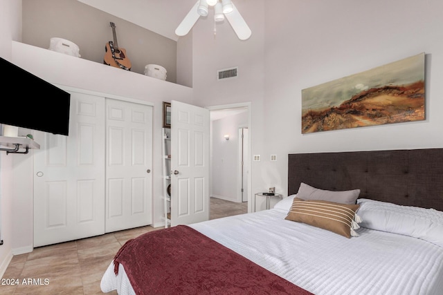 tiled bedroom with ceiling fan, a high ceiling, and a closet