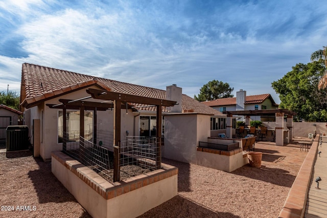 rear view of property with an outbuilding, exterior kitchen, a bar, central AC unit, and a patio