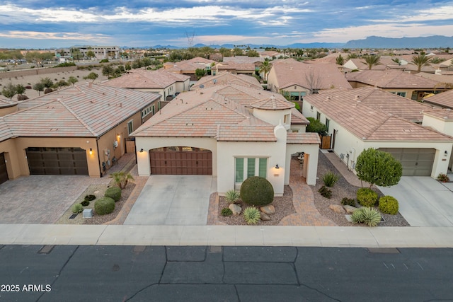 view of front facade featuring driveway, a tile roof, a residential view, an attached garage, and stucco siding