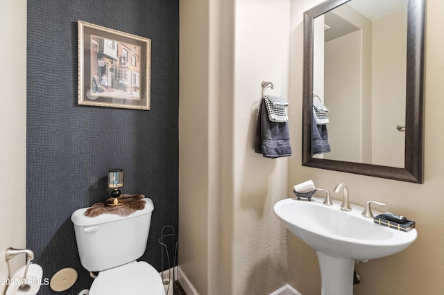 bathroom featuring baseboards, a sink, and toilet