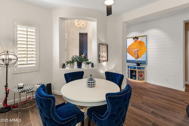 dining space with baseboards, wood finished floors, and an inviting chandelier