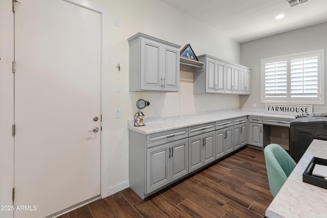 interior space with dark wood-style floors, light countertops, gray cabinets, and washer / dryer