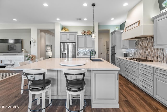 kitchen featuring dark wood-type flooring, gray cabinets, stainless steel appliances, premium range hood, and a sink