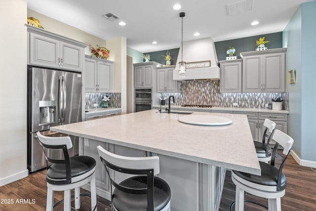 kitchen with visible vents, custom exhaust hood, stainless steel appliances, gray cabinetry, and a sink