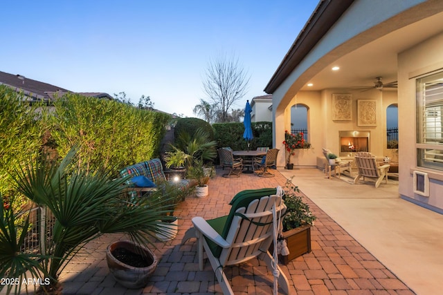 view of patio / terrace featuring a fireplace, outdoor dining area, and a ceiling fan