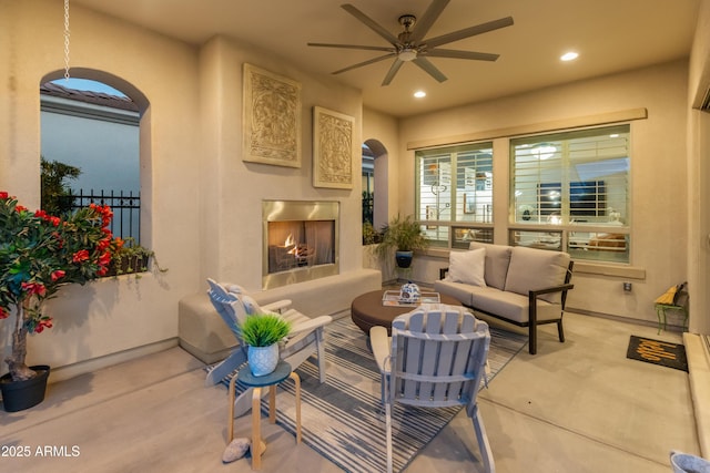 interior space with arched walkways, ceiling fan, a lit fireplace, and recessed lighting