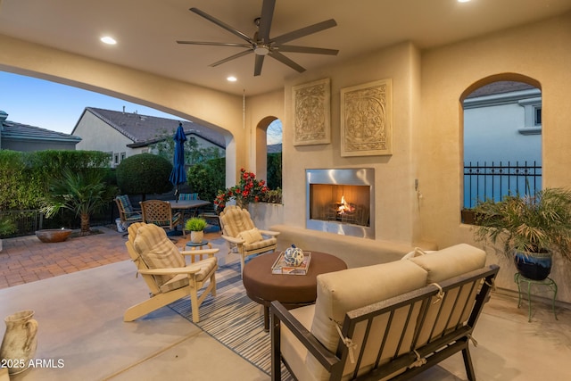 view of patio with an outdoor living space with a fireplace, outdoor dining space, fence, and a ceiling fan