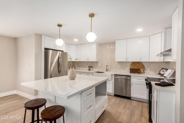 1501 E Sheridan St, Phoenix, AZ 85006 - kitchen featuring stainless steel appliances, a breakfast bar area, light wood finished floors, a kitchen island, and backsplash