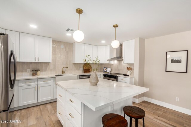 1501 E Sheridan St, Phoenix, AZ 85006 - kitchen with wall chimney exhaust hood, freestanding refrigerator, a breakfast bar, light wood-style floors, and backsplash