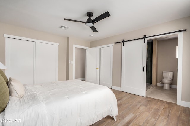 1501 E Sheridan St, Phoenix, AZ 85006 - bedroom with a barn door, light wood-type flooring, multiple closets, baseboards, and ceiling fan