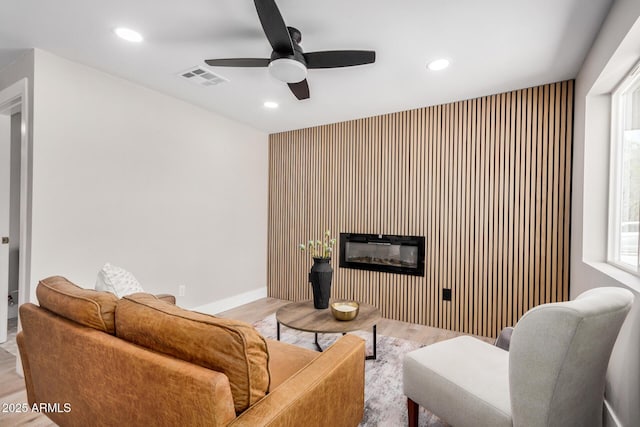 1501 E Sheridan St, Phoenix, AZ 85006 - living area with a glass covered fireplace, wood finished floors, recessed lighting, a ceiling fan, and an accent wall