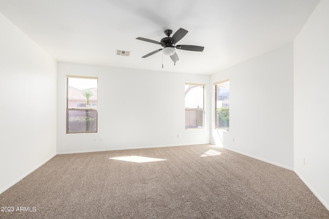 carpeted spare room featuring plenty of natural light and ceiling fan