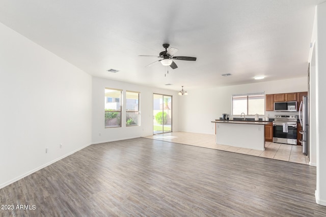 unfurnished living room featuring ceiling fan, a wealth of natural light, sink, and light hardwood / wood-style floors