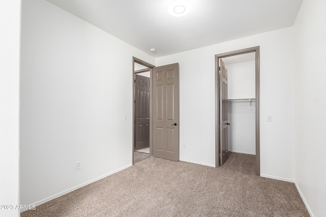 unfurnished bedroom with light colored carpet, a closet, and a walk in closet