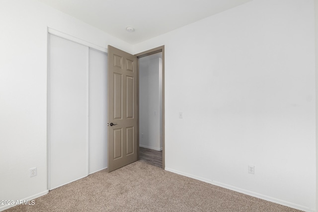 unfurnished bedroom with light colored carpet and a closet